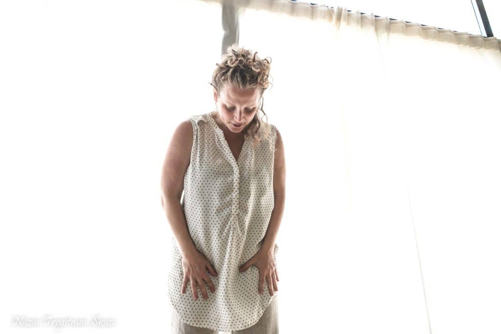 מישהי עומדת בסטודיו עם ידיים על הירכיים ומבט אל הרצפה